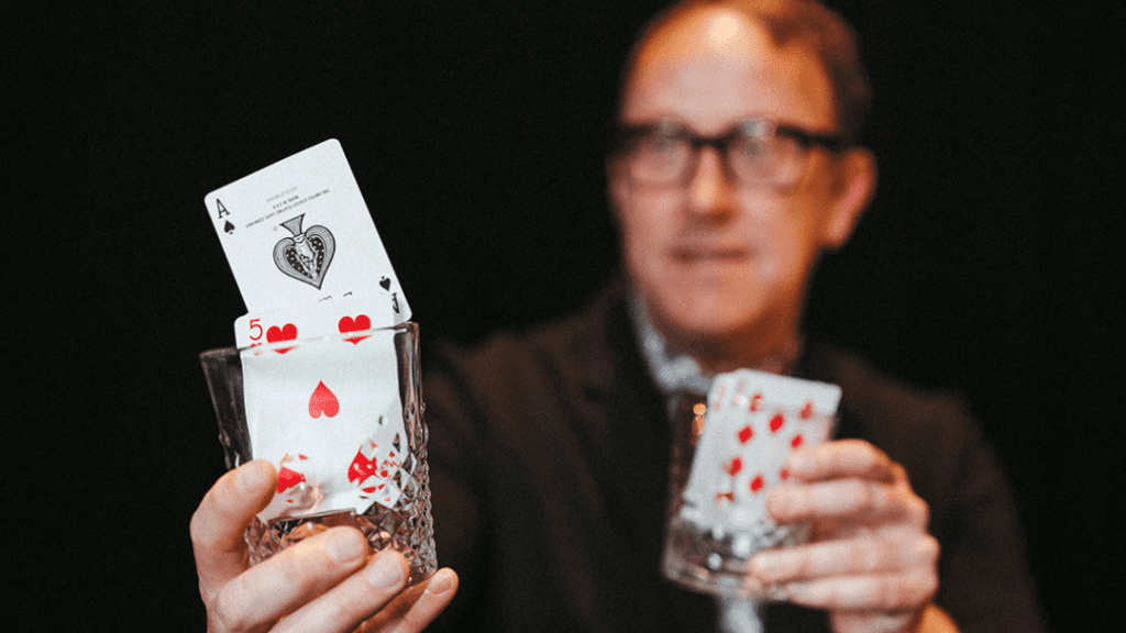 Magician Justin 'Bro' Gilbert holding glasses with cards in them