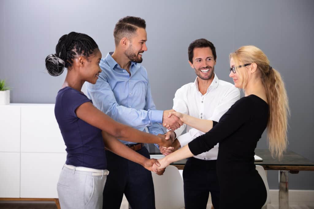 Group Of Multi Racial Businesspeople Shaking Hands With Each Other In Office
